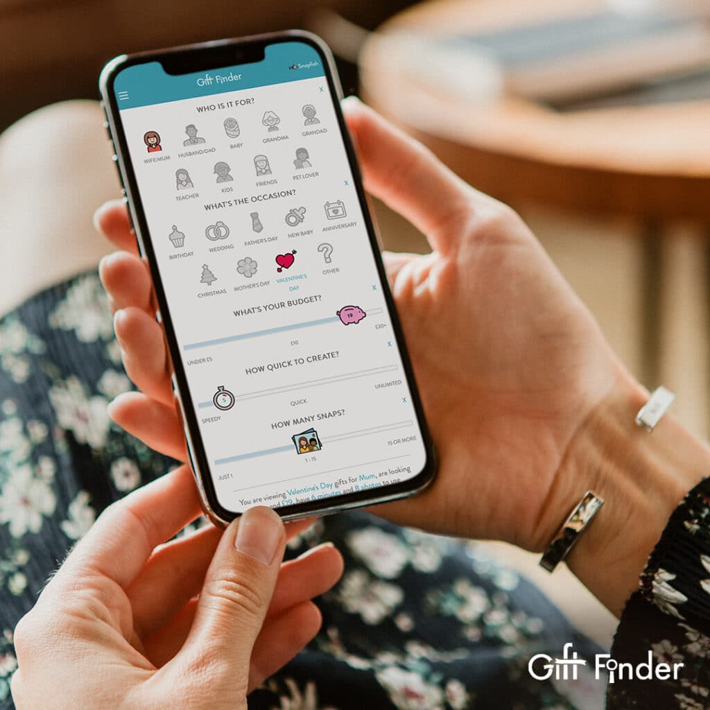 A pair of hands holding a mobile device browsing Snapfish Giftfinder website