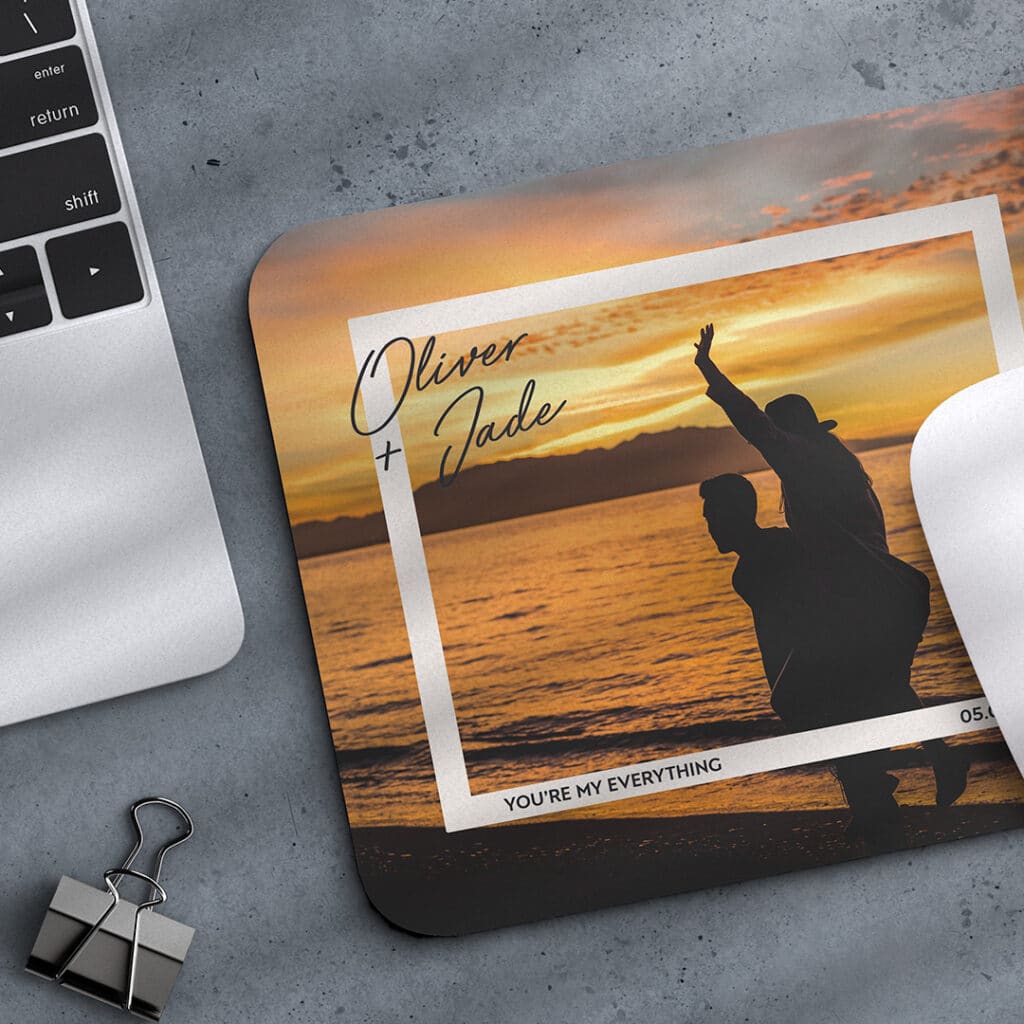 A personalised mouse mat next to a laptop