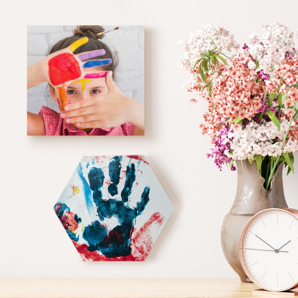 Photo tiles on the wall with a flower arrangement and clock on a desk